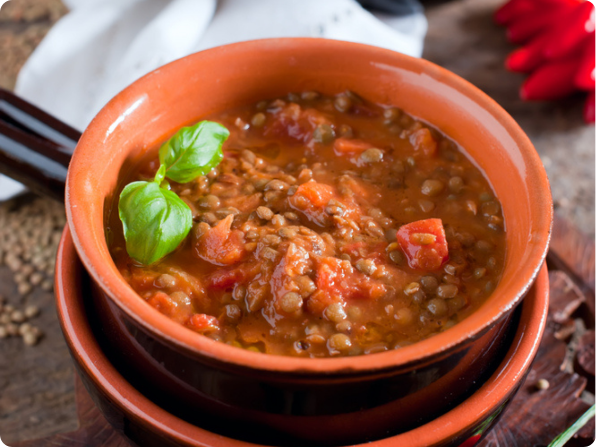 Schüssel mit Linsensuppe mit Tomaten, dekoriert mit Basilikum