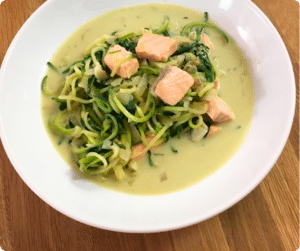 Zoodles mit Lachs in cremiger Sauce – serviert auf einem weißen Teller als gesundes Familiengericht