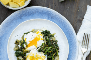 Teller mit pochierten Eiern, auf Spinat und Kartoffeln