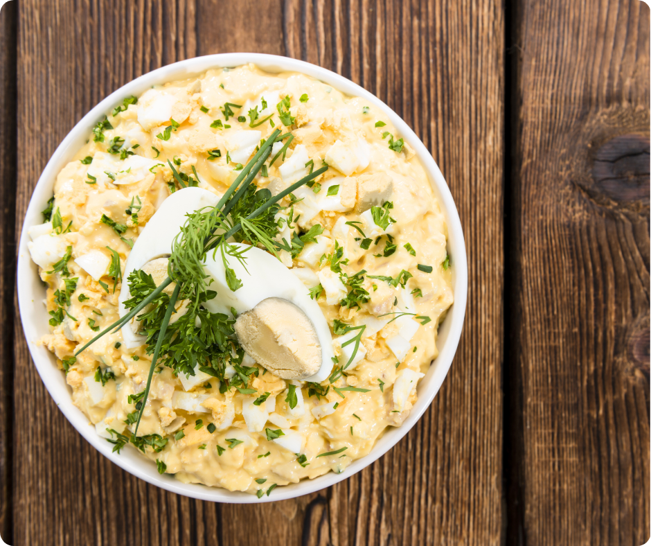 Eiersalat in einer weißen Schüssel auf Holztisch