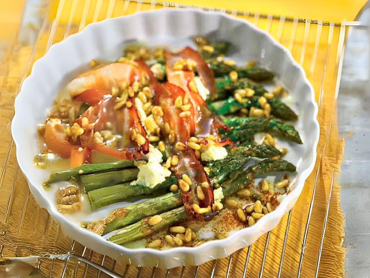Grüner Spargel mit Speck, Sonnenblumenkernen und Feta in weißer Tarteform auf Gitterblech auf gelbem Tuch