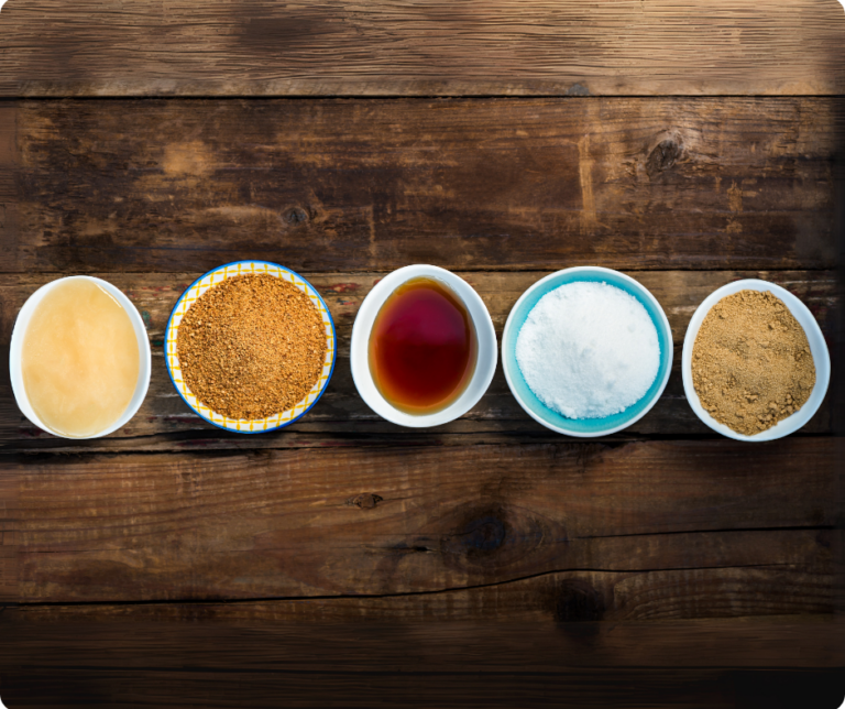 Teller mit verschiedenen Zuckerarten auf einem Holztisch