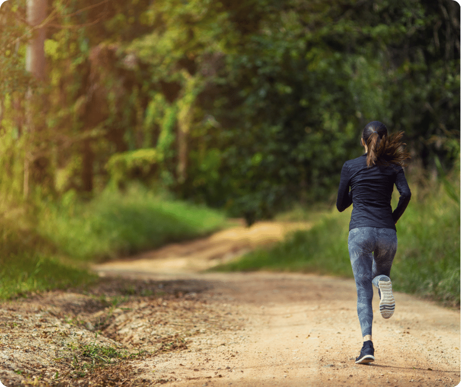 Frau beim Joggen auf einem Waldweg.